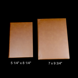 Side-by-side size comparison of personalized cross leatherette journals: compact 5 1/4" x 8 1/4" and larger 7" x 9 3/4" in warm tan faux leather – choose your perfect fit