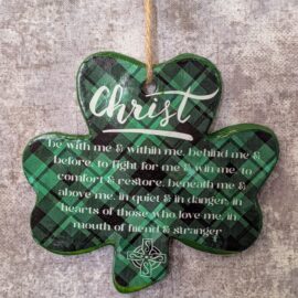 Shamrock shaped clay ornament on a gray background. The ornament has a dark green plaid pattern, and on top of it is the word "Christ" written in a white script. Beneath that are the words "be with me & within me, behind me & before, to fight for me & win me, to comfort & restore, beneath me & above me, in quiet & in danger, in hearts of those who love me, in mouth of friend & stranger". Below that is the outline of a white Celtic cross.