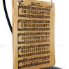 Rectangle shaped ornament with a yellowed hymnal page of "Victory in Jesus" on it. The ornament is hanging by twine from a black ornament stand.