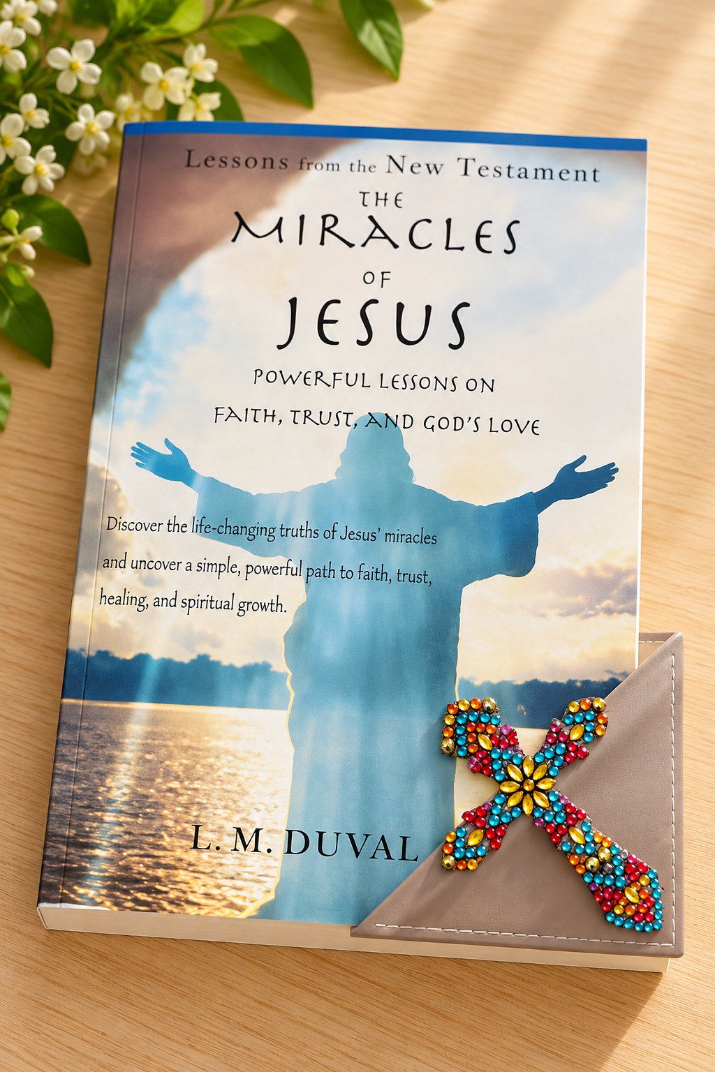 Colorful diamond art cross corner bookmark displayed on The Miracles of Jesus by L. M. Duvall, resting on a light oak tabletop with soft greenery and natural lighting.