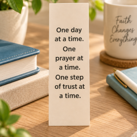 One Day at a Time Christian encouragement bookmark featuring a message about prayer and trust, displayed on a warm wooden table.