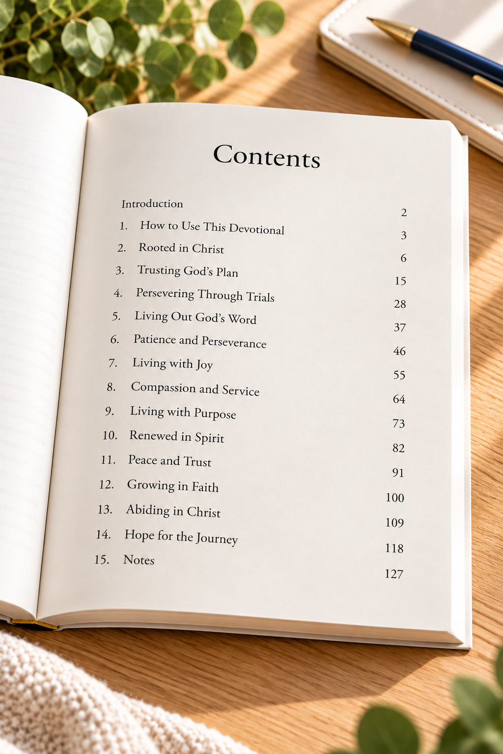 Open paperback of Anchored in Christ: A 90-Day Journey of Faith, Renewal, and Growth by L. M. Duvall, displaying the Table of Contents with devotional themes including Rooted in Christ, Trusting God’s Plan, Living with Joy, Peace and Trust, and Hope for the Journey. The book rests on a light wooden tabletop with soft natural lighting, greenery, a journal, and a pen.